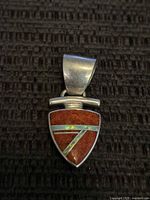 Front view of the shield-shaped pendant showing reddish-brown stone with opal inlay and silver bail.