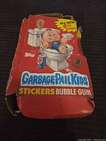 Worn red box for Garbage Pail Kids 6th Series stickers with bubble gum featuring a baby on a toilet illustration.