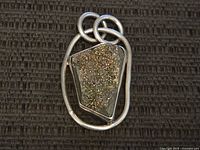 Front view of pendant showing textured druzy stone set in silver.