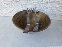 Wooden salad bowl with a fork and spoon salad servers resting inside, displaying natural wood grain and silver serving ends.