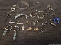 Overview of the lot showing various silver jewelry pieces including bracelets, earrings, rings, pendants, and a brooch.