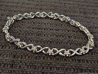Full view of sterling silver tennis bracelet laid flat on black textured surface.