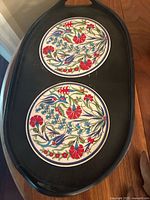 Top view of oval wooden tray displaying both floral ceramic tile inlays