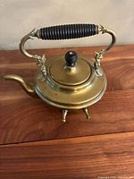 Full view of brass teapot with handle, lid, spout and feet