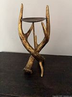 Full view of gold antler candle pedestal on dark surface