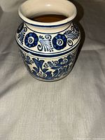 Front view showing blue floral and scroll design on white glazed vase