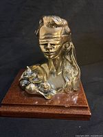 Front view of silver blindfolded lady bust with cornucopia on cherry wood base