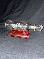 Full view of ship in bottle on wooden stand