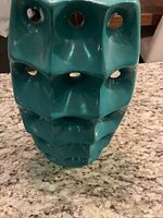 Front view of turquoise ceramic vase showing geometric cutouts