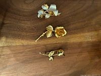 All three floral brooches laid out on wood surface