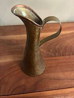 Full view of brass pitcher showing shape, texture and handle
