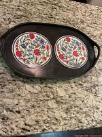 Top view of black wooden tray showing two round Iznik floral tiles