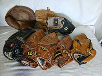 Group of eight baseball gloves arranged on surface