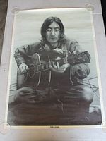 Full view of unframed John Lennon poster held flat by glass discs