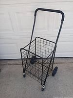 Full view of black metal shopping cart standing upright