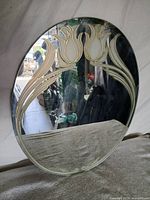 Front view of oval frameless mirror showing etched tulip design