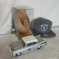 All three Raiders items together: cap, wood football in box, die-cast car