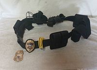full view of duty belt with pouches, attached badge, restraints