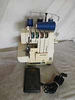 Overall view of Singer Ultralock 14U34 serger with foot pedal and thread cones