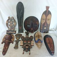 Group shot of nine carved wooden tribal masks and symbol