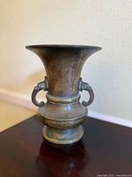 Front view of antique bronze vase showing flared lip and rounded body with pedestal base.