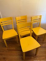 Four yellow Crate and Barrel Ecco dining chairs grouped together showing front and side views on hardwood floor.