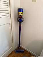 Vacuum standing assembled against wall showing full stick and cleaner head