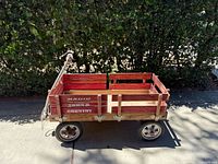 Side view of a vintage Radio Flyer Town & Country wooden wagon showing red slatted wood sides with metal frame and wheels.