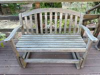 Full view of teak two-seat glider bench showing slatted construction and glider mechanism