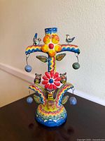 Front view showing floral and bird motifs, single candle socket, hanging ornaments