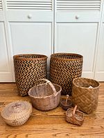 Photo showing five vintage woven baskets including two large hamper size with zigzag pattern, and three smaller baskets of varying shape and style.