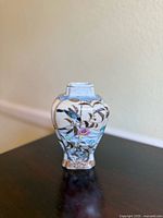 Front view of vintage Chinese porcelain vase showing floral and landscape painted designs on curved body and square mouth