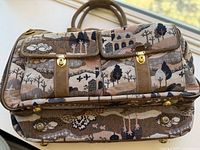 Front and side view of the vintage overnight bag showing the suede handles, tapestry countryside and unicorn design, gold-tone locks and metal feet.