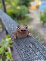 Front view of the vintage ceramic frog pottery figure showing facial features and body details.