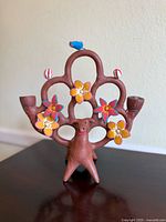 Front view of the handmade clay Tree of Life sculpture with bird and flower decorations and two candle holders.