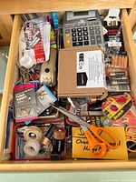 Drawer showing all assorted office supplies, hardware items, batteries, film, and calculator