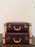 Two stacked leather suitcases showing size difference and overall style
