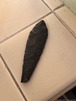 Full view of obsidian spear tip on tile surface
