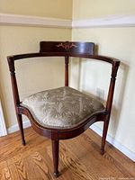 Full view of vintage upholstered corner chair with wooden frame and patterned fabric seat.