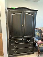 Front view of black armoire showing doors and drawers
