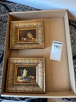 Both framed paintings in shipping box showing size and frames