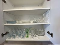 Cupboard shelves with assorted blue goblets, green goblets, plates, crystal bowls and tray
