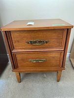 Front view of wooden side table with two drawers and brass-tone handles