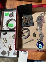 Overview of both boxes showing sterling pendant, 800 bracelet, charm bracelet, pendants, brooch, stick pin, hamsa wall hanging and golf accessory pouch