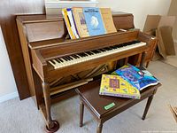 Front view of Wagner upright piano with bench and books
