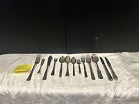 Full layout of 14 mixed flatware pieces on cloth