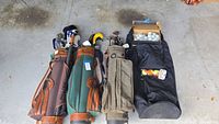 Four golf bags and travel case with clubs and balls overview