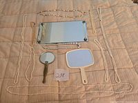 All items laid out: mirrored tray, two hand mirrors, eight necklaces