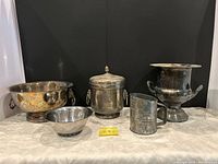 Front view of all five silver-plated serving pieces on table