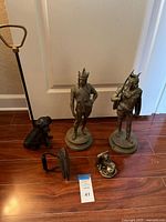 Group shot showing all items: two brass Viking statues, sad iron, fireplace poker, dog figure